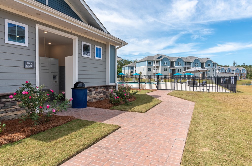 a walkway leading to a house with a yard and a pool