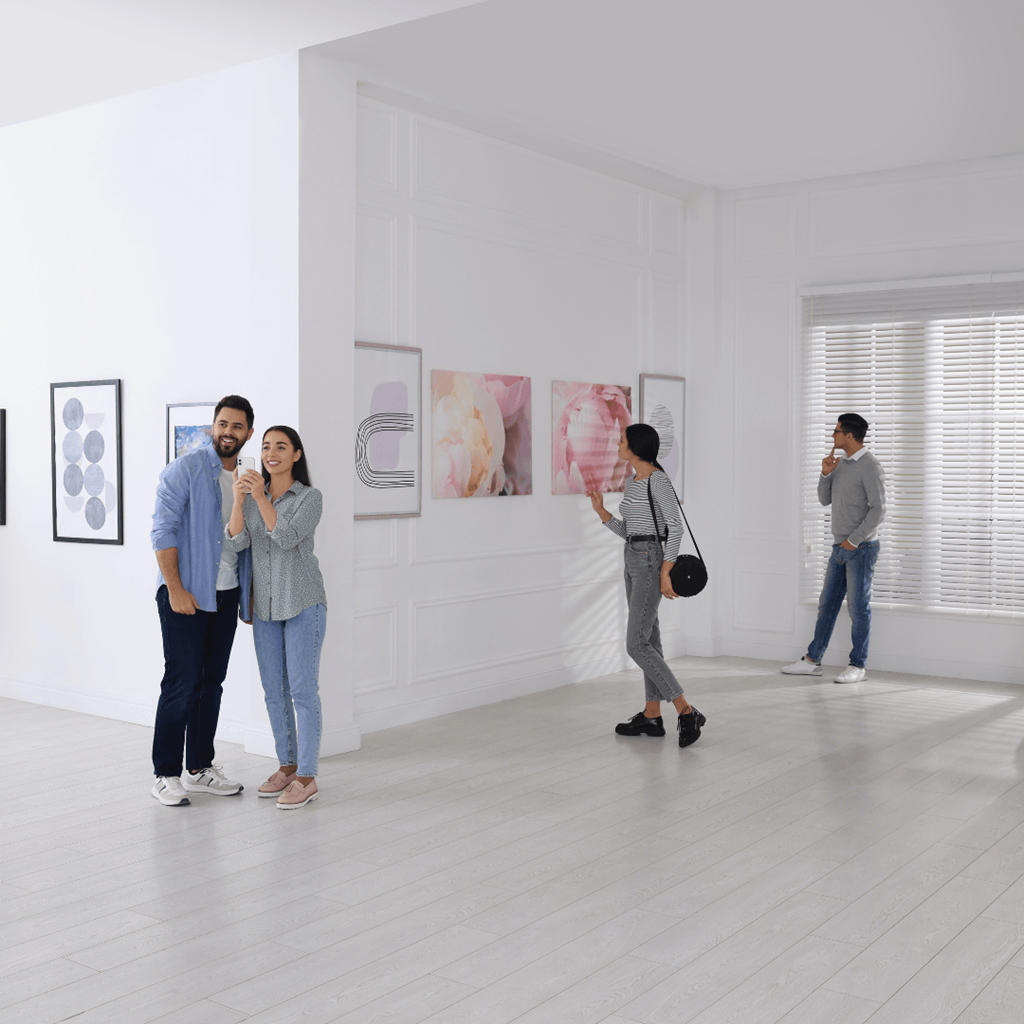 a group of people standing in an art museum looking at paintings