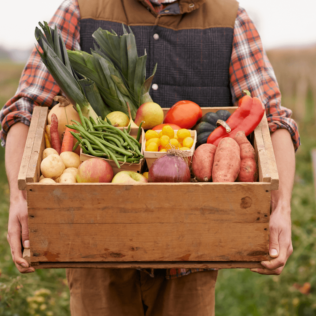 a man holding a wooden crate full of fruits and vegetables