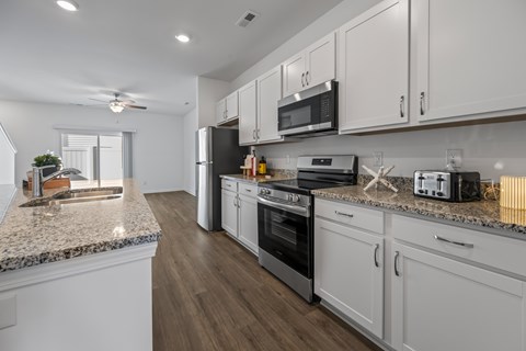 A kitchen with white cabinets and a granite countertop.