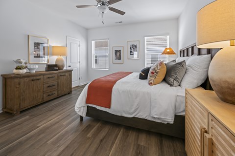 A bedroom with a bed, nightstand, and a wooden dresser.