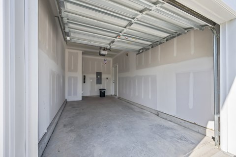A spacious garage with a white ceiling and walls, and a concrete floor.