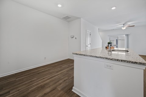 A spacious kitchen with a granite countertop and wooden flooring.