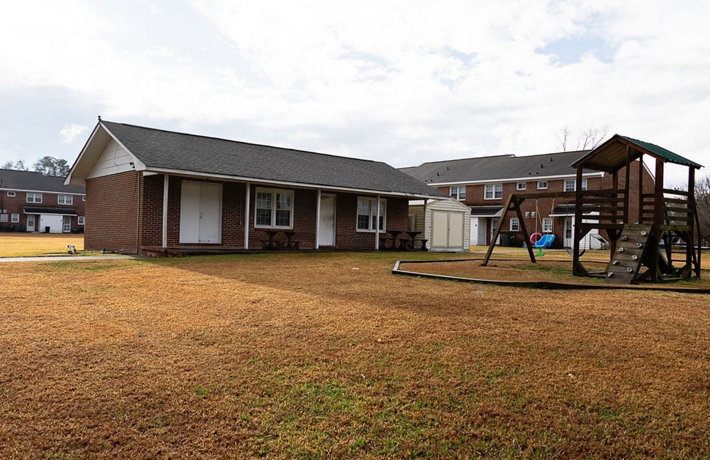 a play yard with a swing set in front of a house