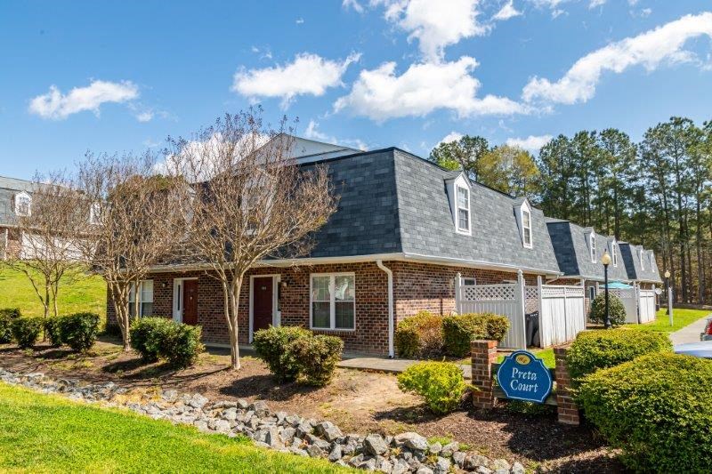a red brick house with a blue roof and a blue and white sign