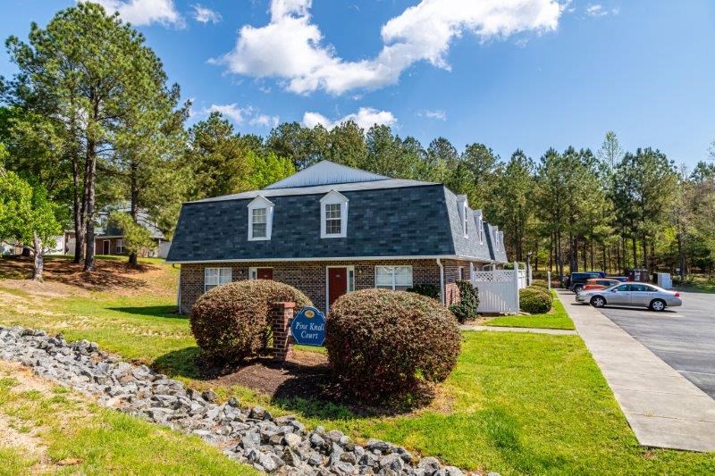 a small blue house with a stone wall and trees