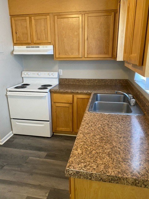 a kitchen with a white stove top oven next to a sink