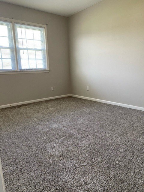 a room with a carpeted floor and two windows