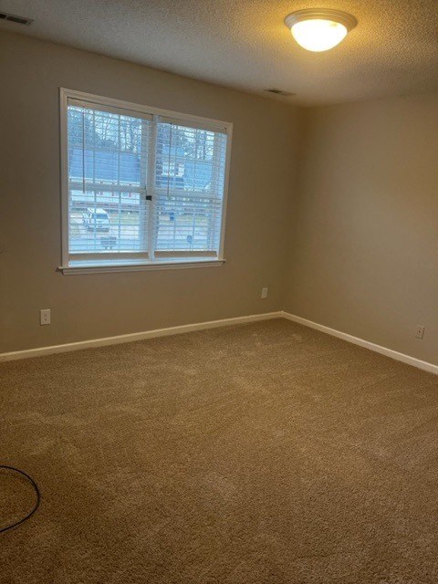 an empty living room with a window and carpet