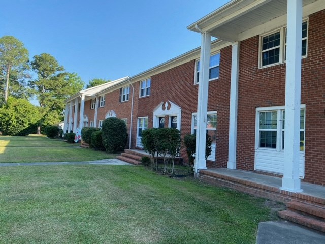 a view of the front of a brick building with white columns