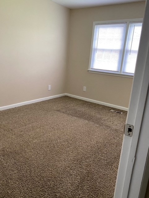 an empty room with a carpeted floor and a window