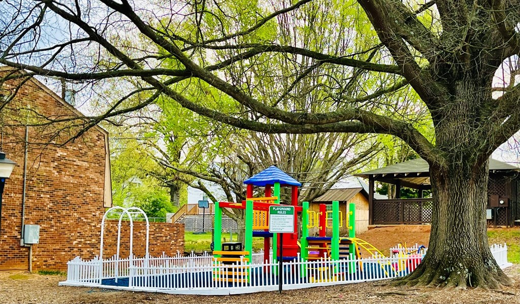a childrens playground with a tree and a white fence