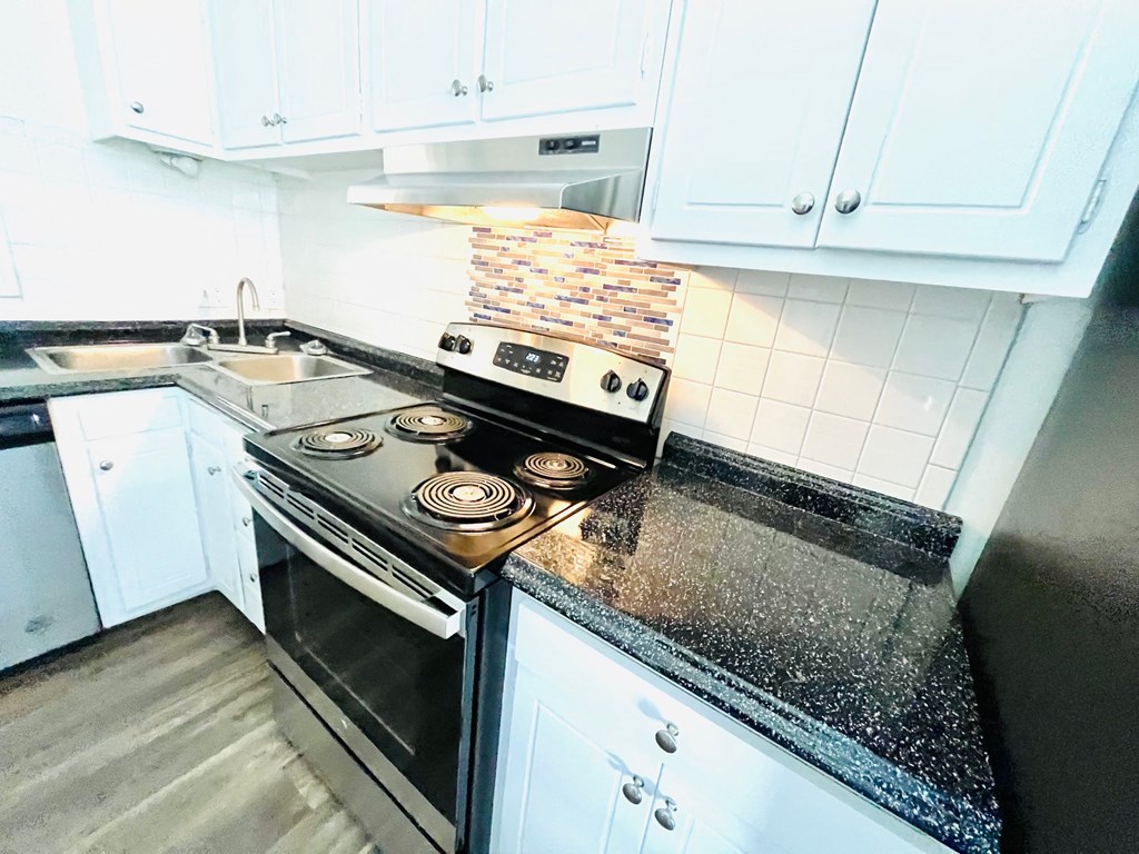 a kitchen with white cabinets and a stove and a sink