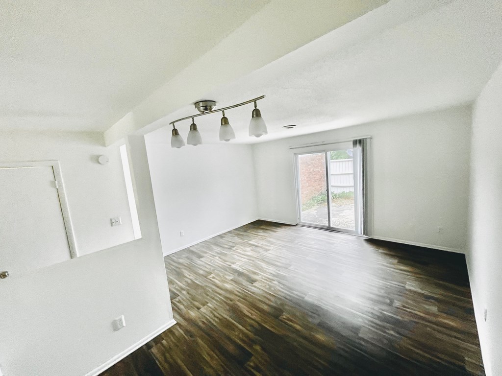 an empty living room with a wood floor and white walls
