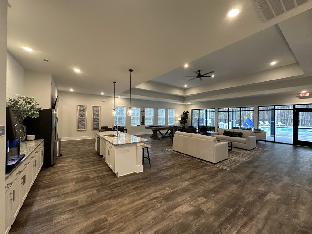 A spacious kitchen and living room with wood flooring and white cabinetry.