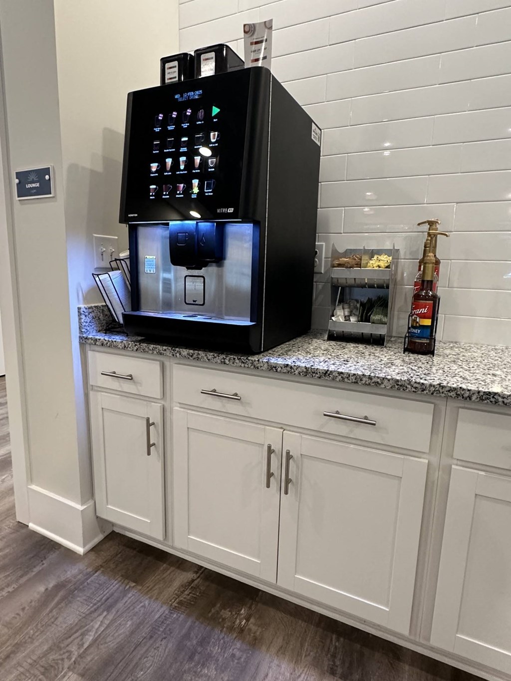 A black coffee machine is on top of a granite countertop.