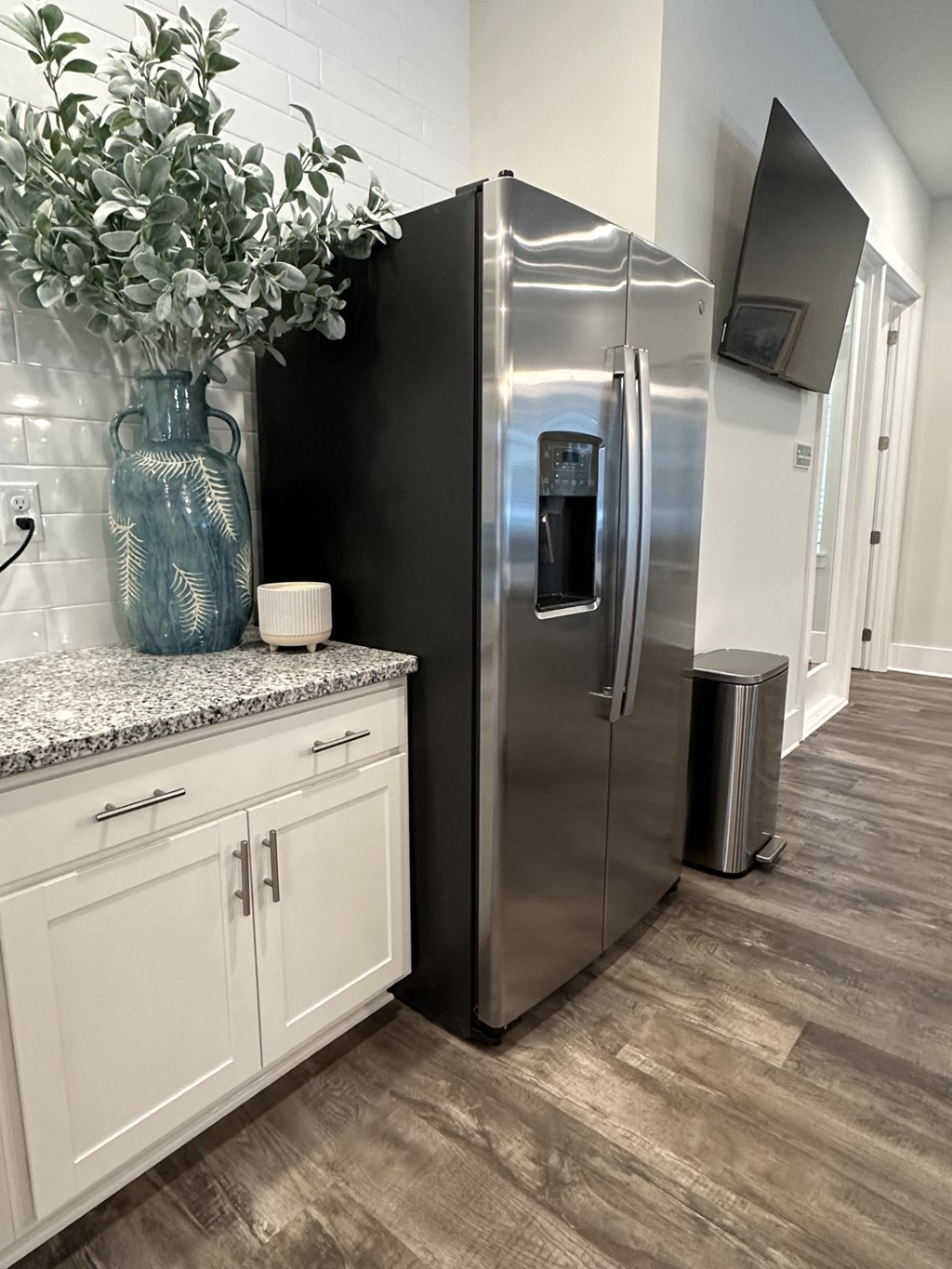 A kitchen with a stainless steel refrigerator and white cabinets.