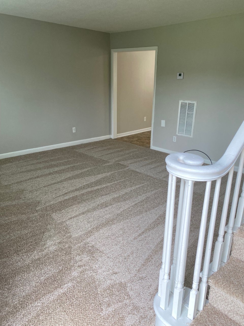 an empty room with a staircase and a door in the background