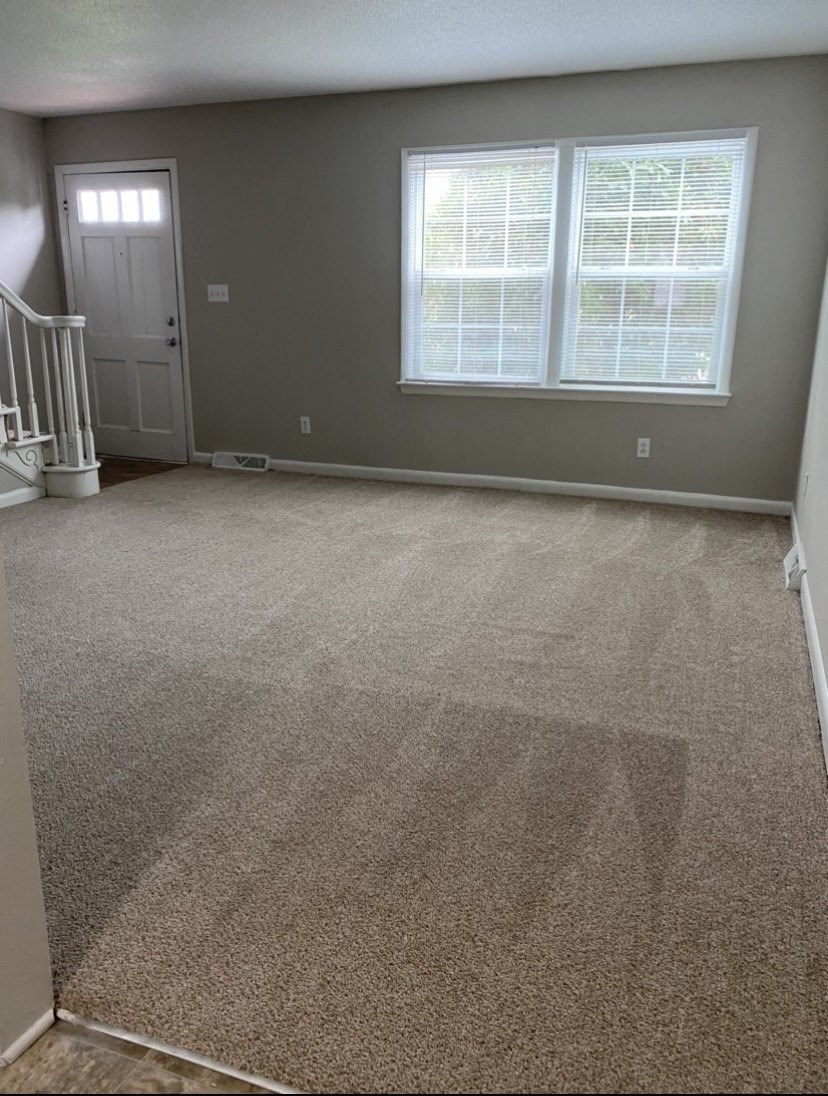 an empty room with a white door and two windows