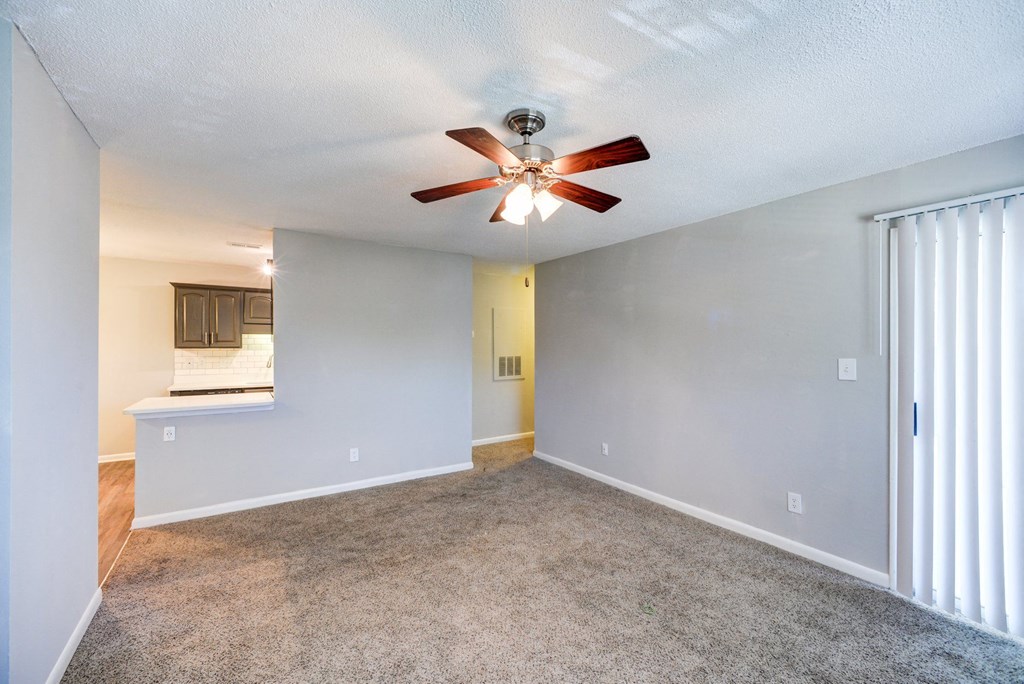 an empty living room with a ceiling fan
