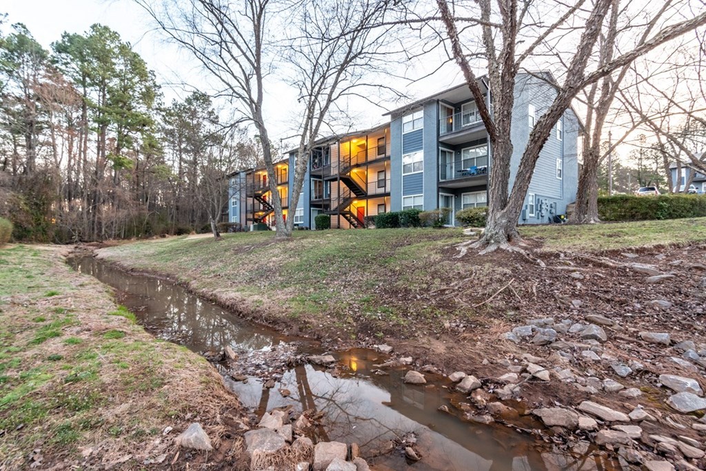 the stream in front of a house with a building in the background