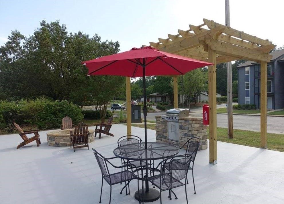 a patio with a table and chairs under a red umbrella
