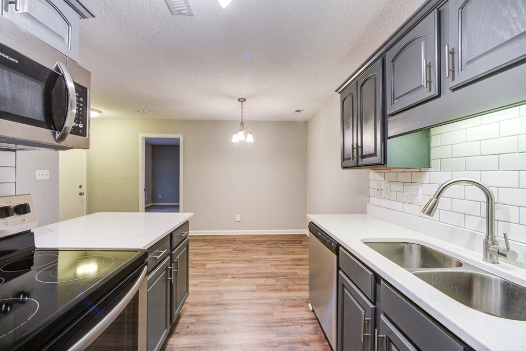 an empty kitchen with stainless steel appliances and white counter tops