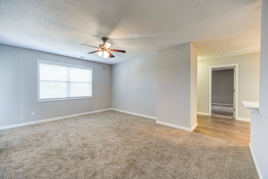 an empty living room with a ceiling fan and a window