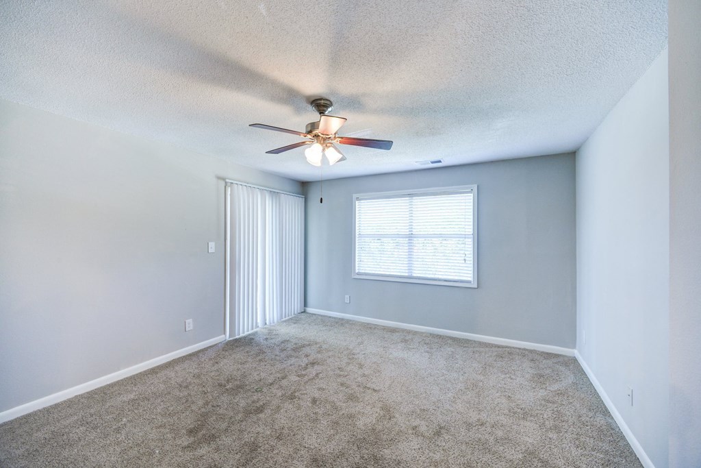 an empty living room with a ceiling fan and a window