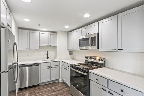 A modern kitchen with white cabinets and stainless steel appliances.