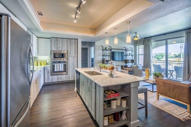 a kitchen with an island and a living room in the background