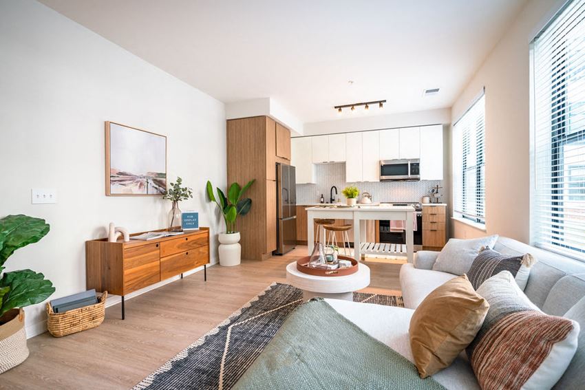 a living area with a couch coffee table and a kitchen in the background - Photo Gallery