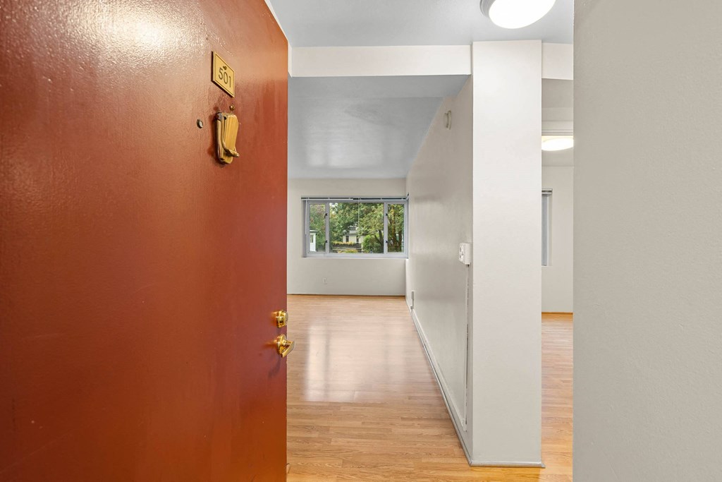 an empty room with a red door and a hallway to a white room at Celio Apartments, Portland, Oregon