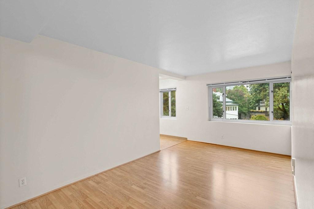 a living room with white walls and a window and wooden floors at Celio Apartments, Portland, OR