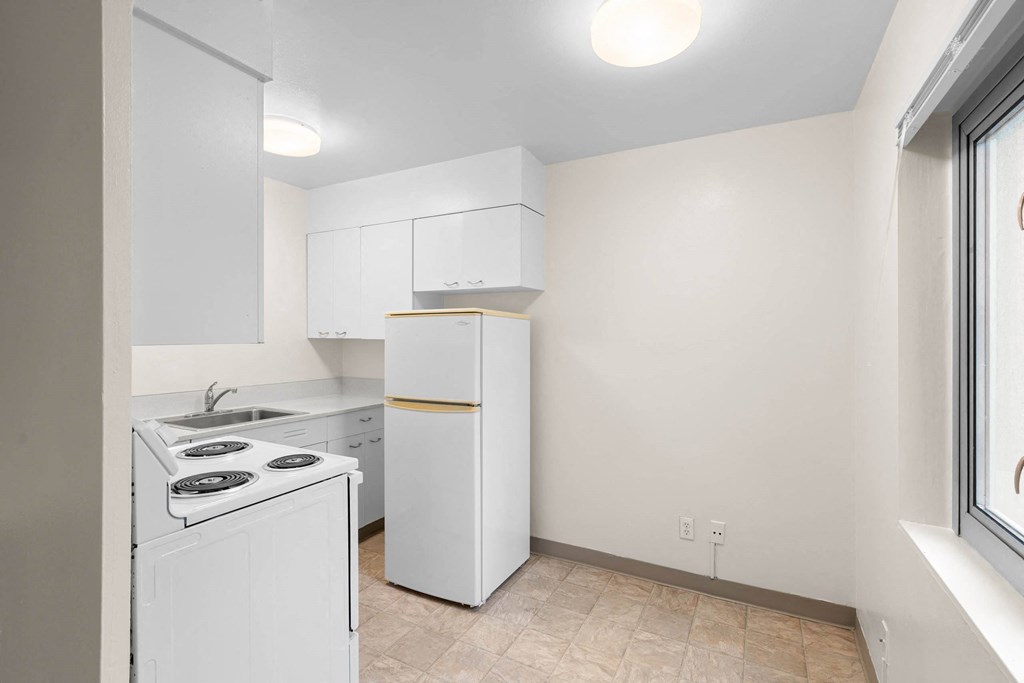 a white kitchen with white appliances and a window at Celio Apartments, Oregon, 97205