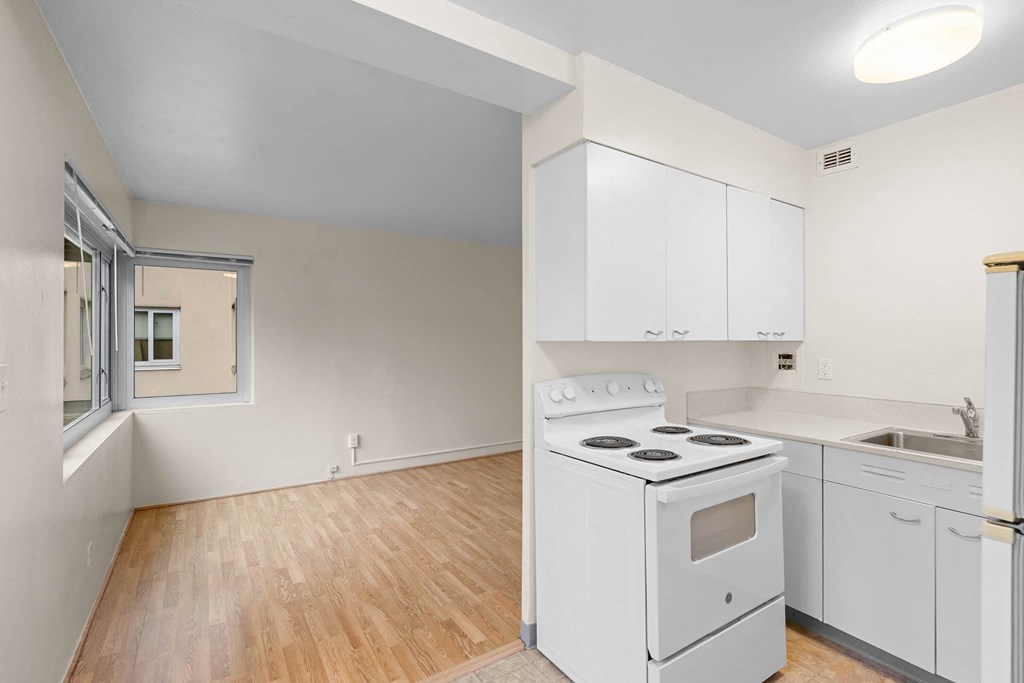 an empty kitchen with white appliances and white cabinets at Celio Apartments, Portland, OR, 97205