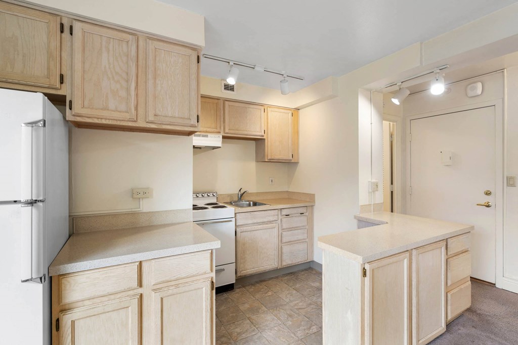 a kitchen with white appliances and wooden cabinets at Celio Apartments, Portland, OR, 97205