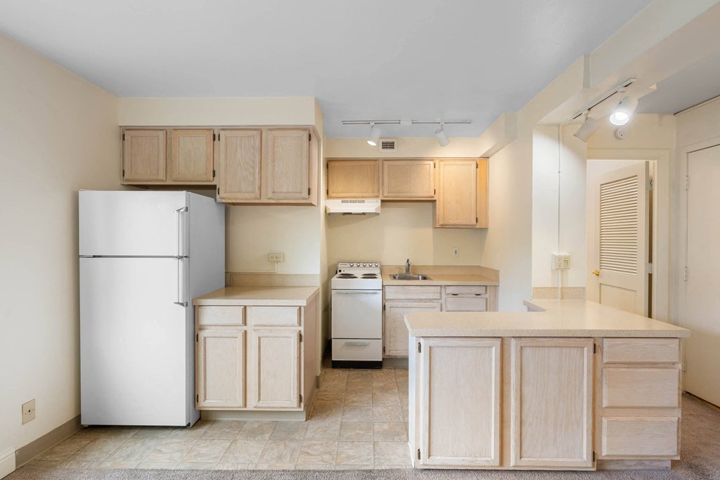 a kitchen with wood cabinets and a refrigerator and a stove at Celio Apartments, Portland, Oregon