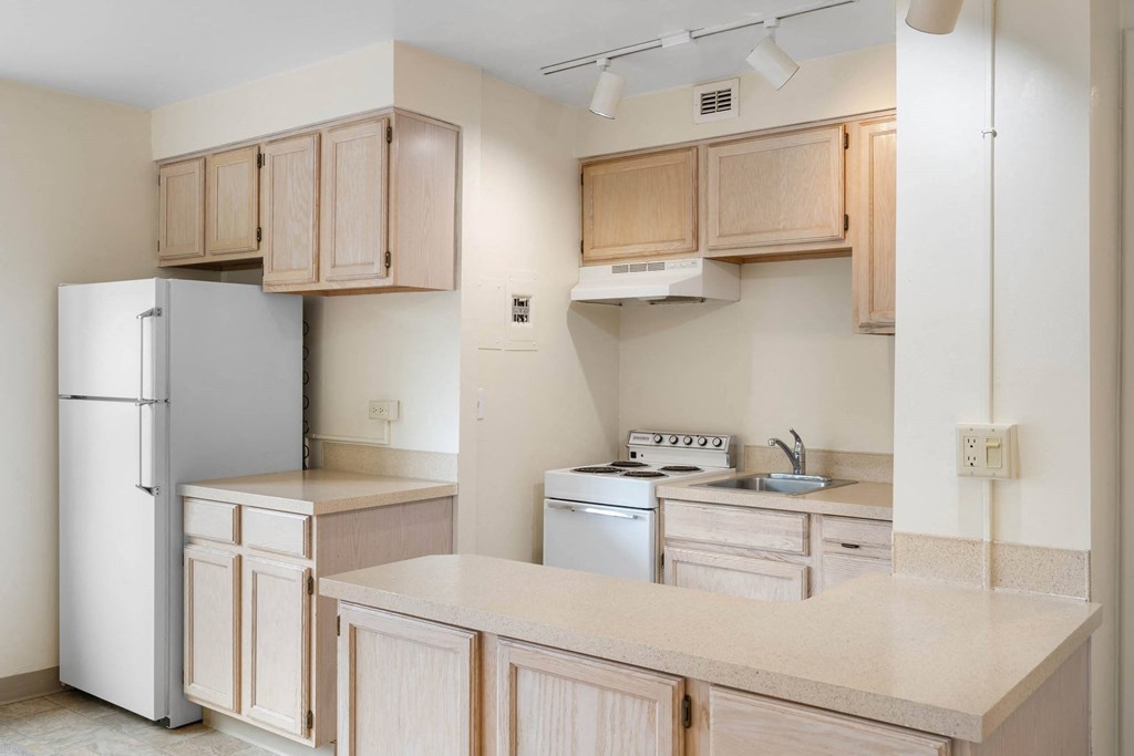 an empty kitchen with white appliances and wooden cabinets at Celio Apartments, Portland, OR, 97205