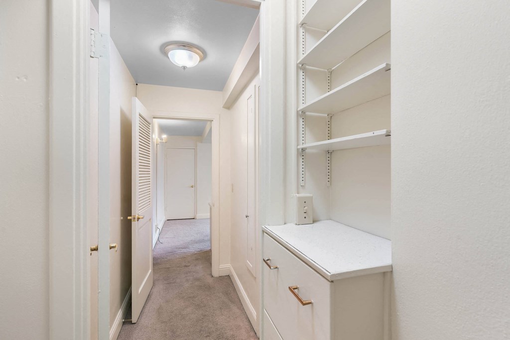 a walk in closet with white cabinets and a white counter at Celio Apartments, Oregon