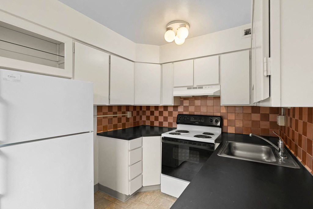 a kitchen with black counter tops and white appliances at Celio Apartments, Portland, OR, 97205
