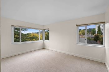 a living room with three windows and a carpeted floor