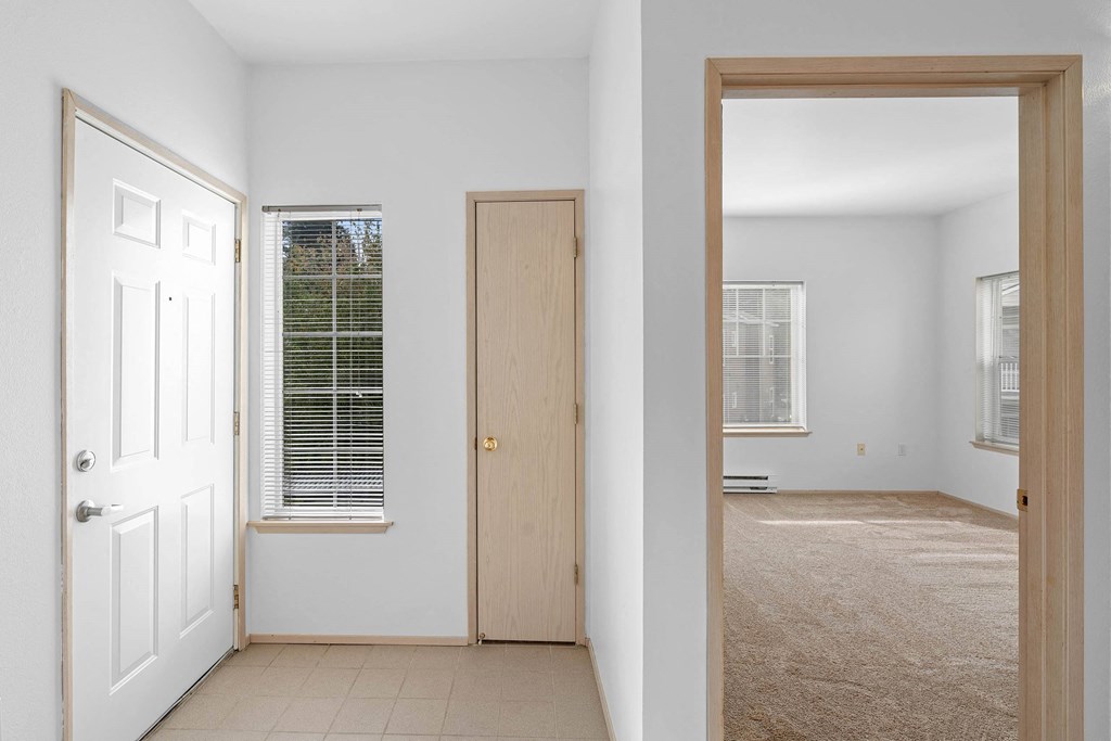 an empty room with a door to a bedroom and a window