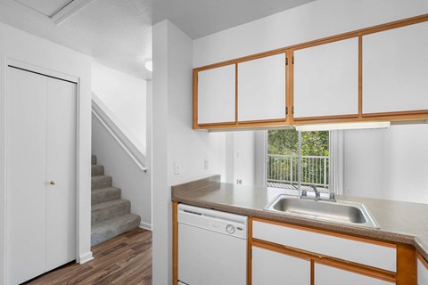 a kitchen with a sink and a window and a staircase