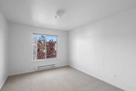 Vacant bedroom with window and baseboard heating at Summer Creek Apartments, Tigard