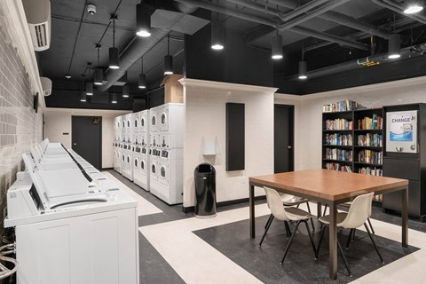 Laundry facility with seating and bookshelf at Vista St Clair Apartments, Portland