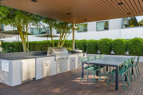 the outdoor kitchen has stainless steel appliances and a table with chairs