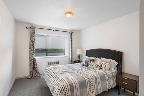 Bedroom with patterned bedding and window view at Vista St Clair Apartments, Portland, OR