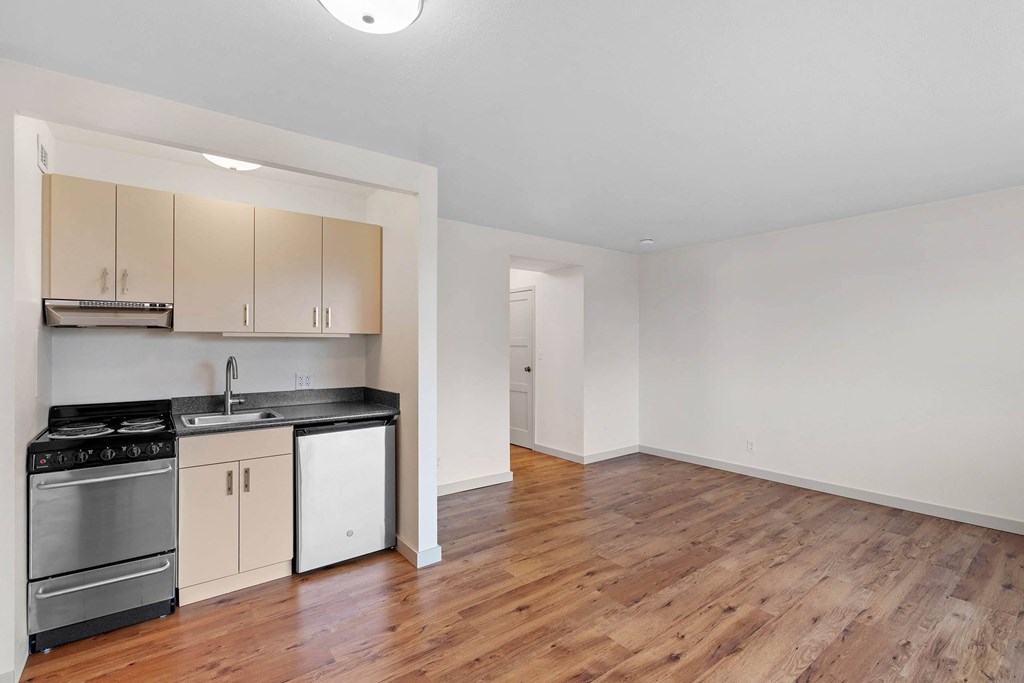 an empty living room with a kitchen with a stove and refrigerator at Vista St. Clair, Portland, 97205
