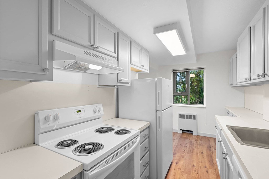 a white kitchen with white appliances and white cabinets at Vista St. Clair, Portland, OR